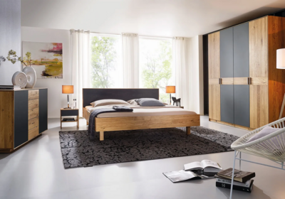 Holzschmide Jaso Bett in Eiche mit Polsterkopfteil, Kommode Jaso in Wildeiche mit anthraziten Mattglastüren, Kleiderschrank Jaso in Wildeiche mit Querriegeltüren